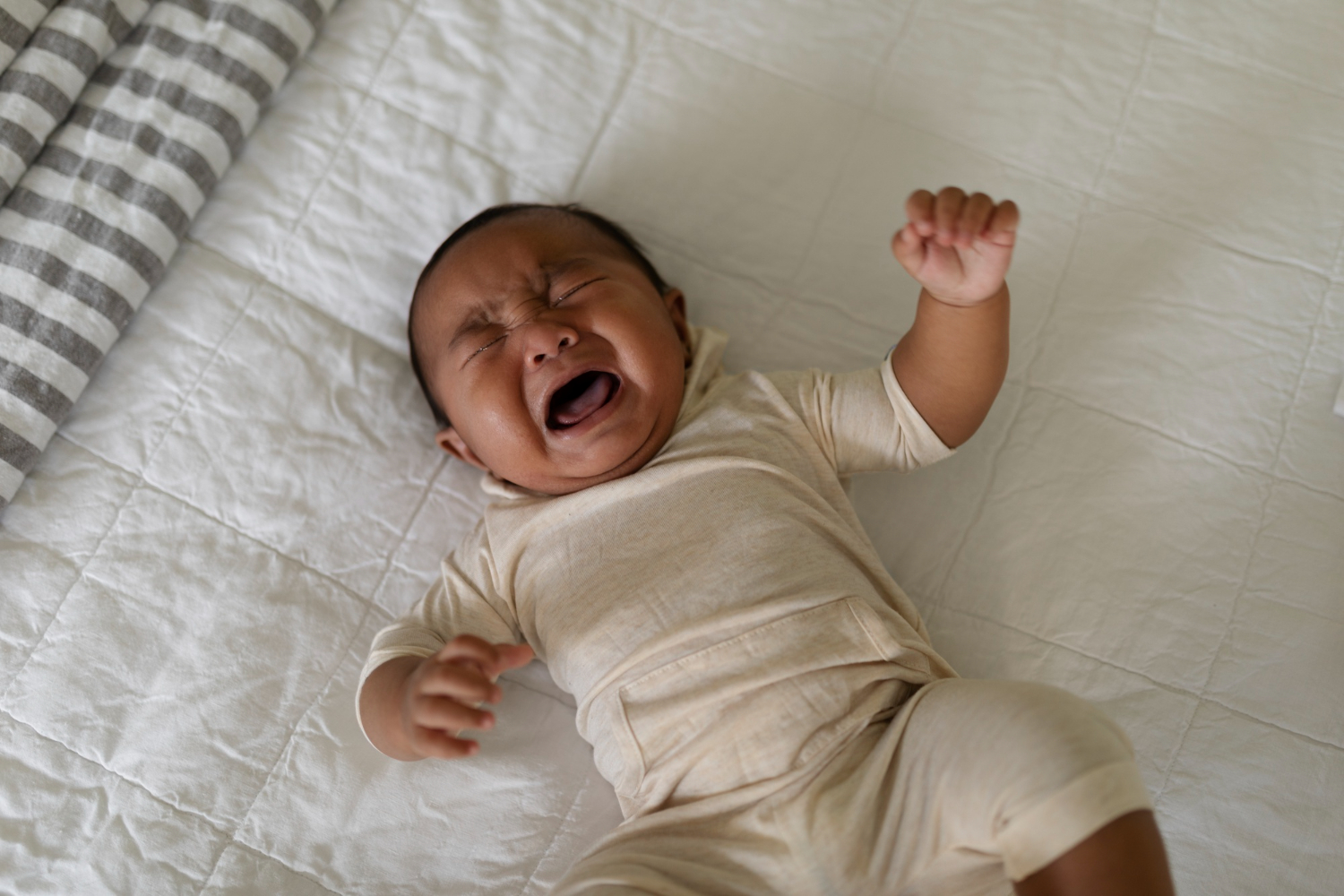 a toddler crying on the bed