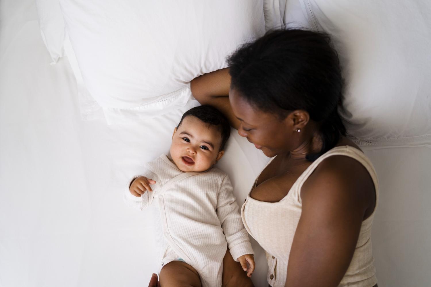 a mom and her baby lying down on the bed