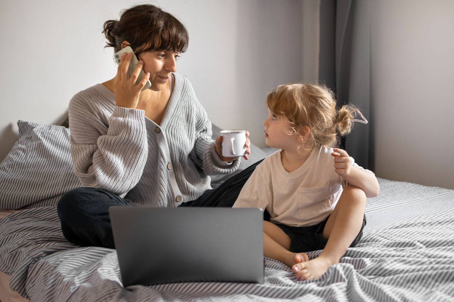 A mom and her baby with the mom holding a cup and taking a call