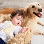 a toddler lying down close to a dog