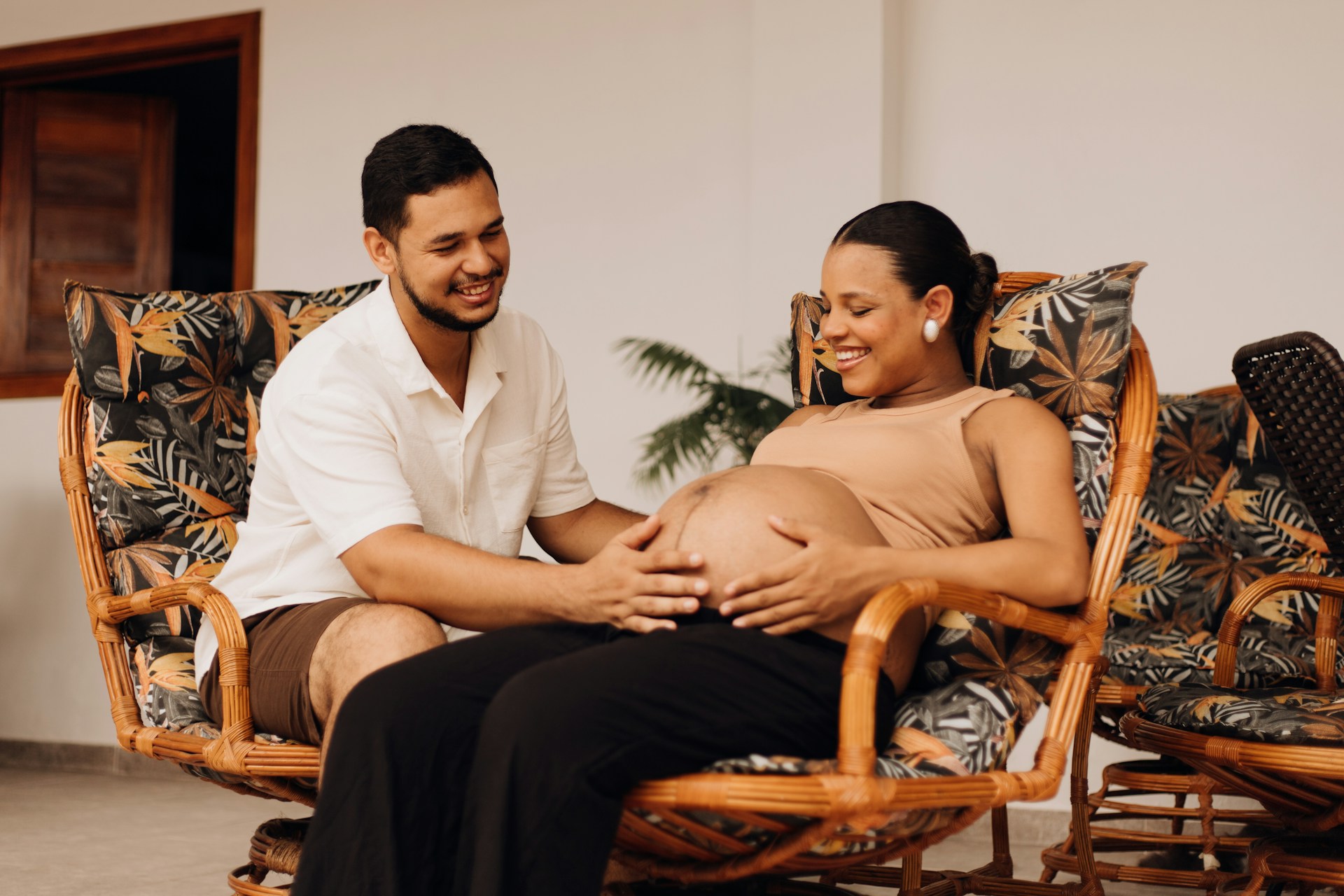 a pregnant woman and her husband smiling